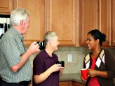 Older couple sharing a coffee with younger woman in kitchen